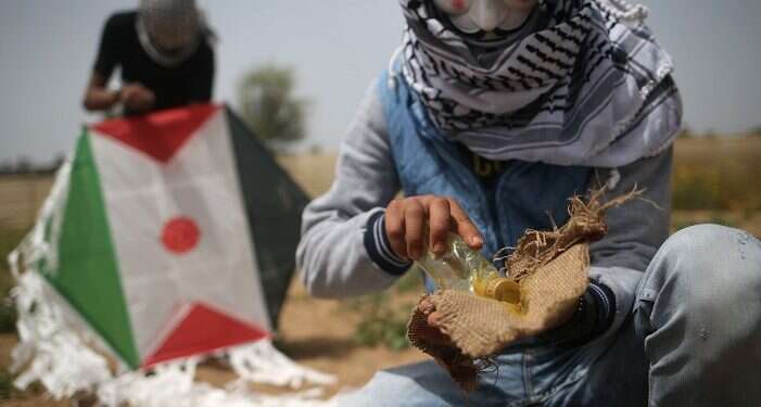 A kite carrying an incendiary device flies over the Israel-Gaza Strip border|A burned field in Kibbutz Be'eri|Palestinians prepare an incendiary device to be attached to a kite before trying to fly it over the border fence with Israel ||