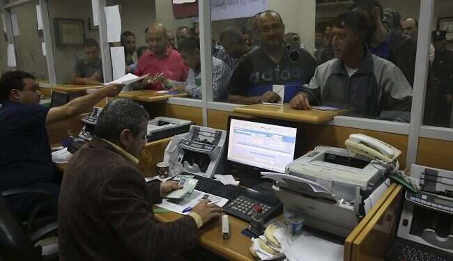 Hamas government employees queue to receive 60% of their overdue salaries at the main Gaza Post Office ||