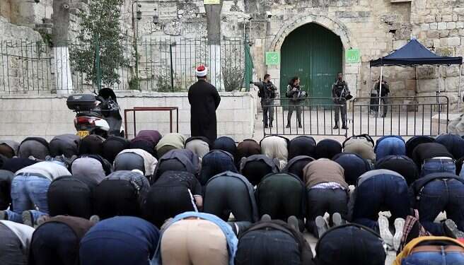 Palestinians pray as Israeli border police guard the entrance to the Temple Mount Police shutter Temple Mount after Palestinian firebombing