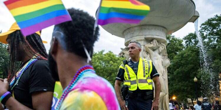 A police officer watches the crowd at the conclusion of the Capital Pride Parade Neo-Nazis deface Israeli flag during Detroit pride parade