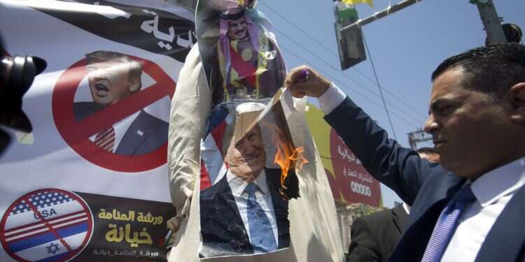 A Palestinian man burns a photo of the US President Donald Trump and King Hamad al-Khalifa of Bahrain during a protest against the American-led Mideast peace conference in the village of Halhul near the West Bank city of Hebron, Monday, June 24, 2019 Once again, the PA shows it doesn't care about having a viable state