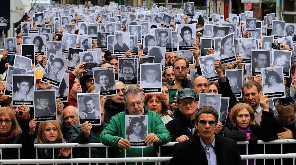 People holding pictures of victims of the 1994 bombing attack against the Argentine Israelite Mutual Association (AMIA) Jewish community center that killed 85 people and injured 300 PM thanks Argentina for listing Hezbollah as terrorist entity