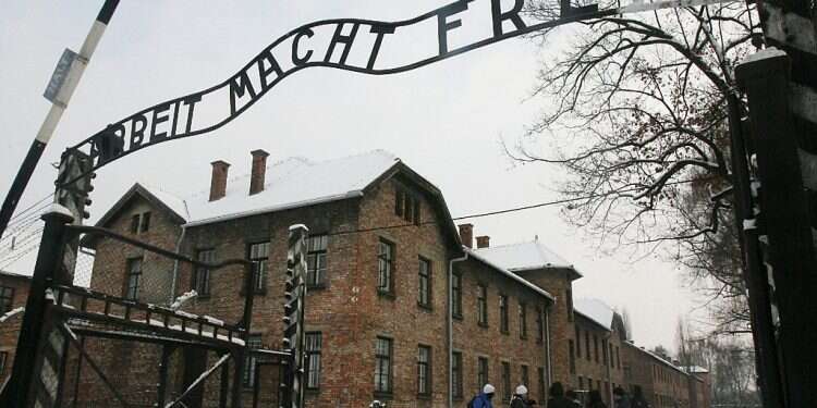 Tourists pause near the main entrance of the Auschwitz concentration camp Florida principal removed after siding with parents who questioned Holocaust
