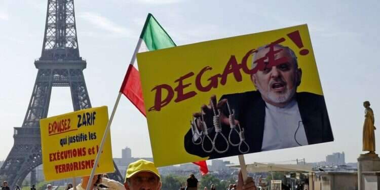 Demonstrators with the National Council of Resistance of Iran demonstrate at Trocadero Square on Friday, holding up signs telling Iranian Foreign Minister Javad Zarif to 'Get out!' Iranian FM Zarif talking to French counterpart at G-7 summit