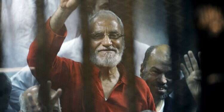 Muslim Brotherhood spiritual leader Mohammed Badie waves from a defendant's cage in a makeshift courtroom at the national police academy, in eastern Cairo on May 16, 2015 Egypt sentences 11 Muslim Brotherhood leaders to life for spying for Hamas