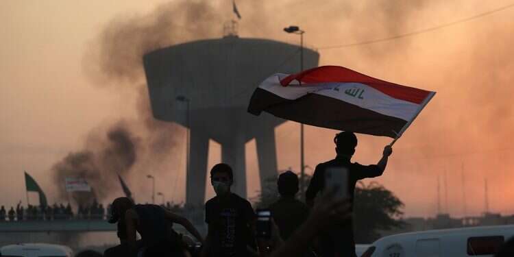 Anti-government protesters wave flags during a demonstration in Baghdad 11 killed as protests against Iranian meddling in Iraq, government corruption intensify