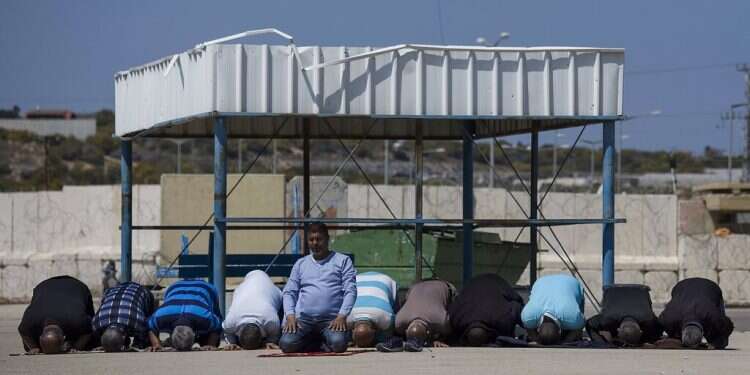 In this March 26, 2017 file photo, Palestinian residents of the Gaza Strip pray as they wait on the Israeli side of the Erez crossing to return home Report: Israel issuing more work permits for Gazans