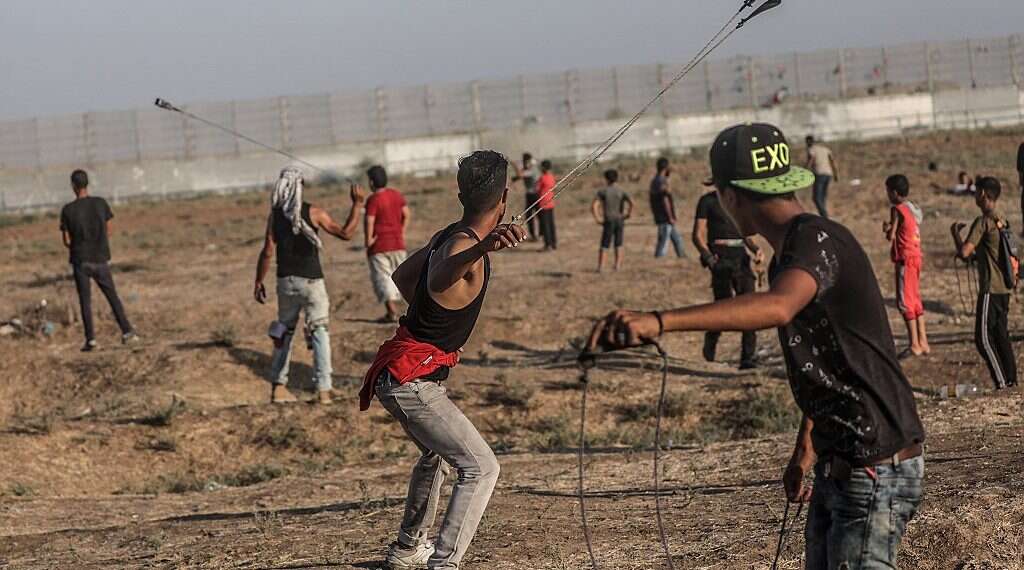 Palestinian protesters throw rocks during clashes at the Gaza border Funneling hatred