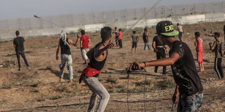 Palestinian protesters throw rocks during clashes at the Gaza border Funneling hatred