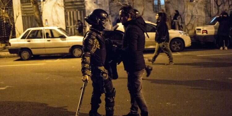 In this photograph taken Saturday, Jan. 11, 2020, A protester confronts an Iranian police officer while demonstrators gather in front of Amir Kabir University in Tehran, Iran, to remember victims of a Ukrainian airplane shot down by an Iranian missile WATCH: Iranian protester risks life to talk to i24NEWS