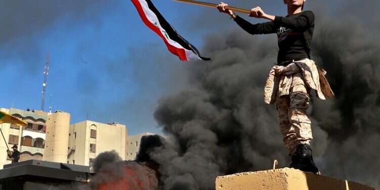 Protesters burn property as a militiaman waves an Iraqi flag in front of the US embassy compound, in Baghdad, Tuesday Iran plays its Trump card in Iraq