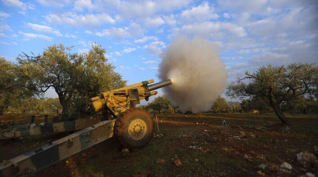 Turkish-backed Syrian fighters fire a howitzer near the village of Neirab, in Idlib province, Syria, Monday Syrian troops hit civilian sites in last rebel-held area