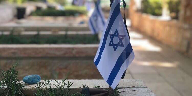 An Israeli flag placed on a grave in the military cemetery on Mount Herzl Nationwide lockdown likely for Memorial, Independence Day events