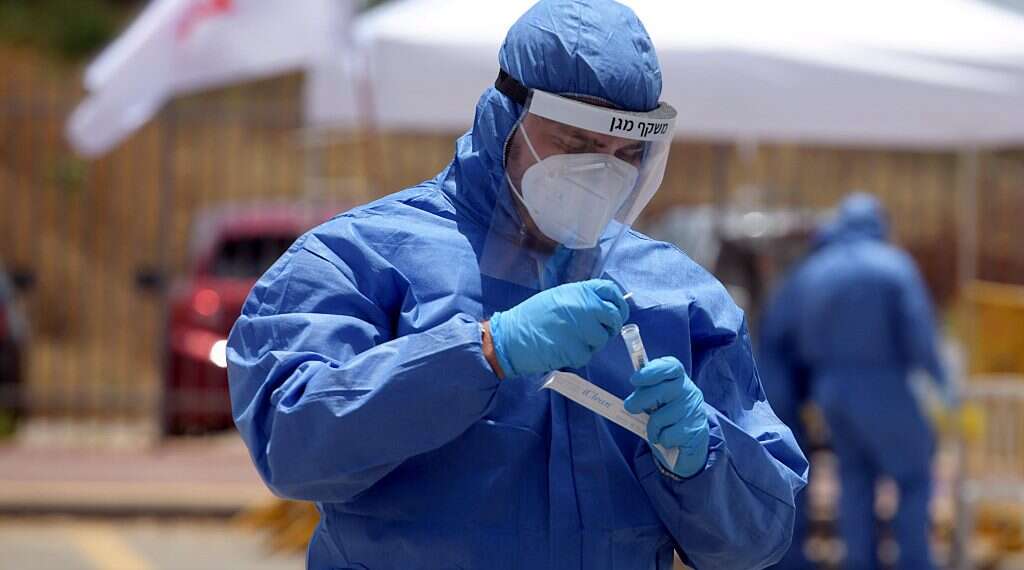 A lab technician at a coronavirus testing drive-through center in Tel Aviv Daily corona tally spikes to 85, Health Ministry warns of new outbreak