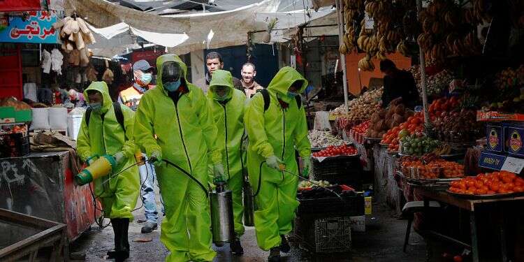 Workers wearing protective gear spray disinfectant as a precaution against the coronavirus at the main market in Gaza City Watchdog: Millions earmarked for Palestinian corona aid funneled to terrorist-linked groups