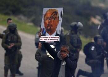 A Palestinian demonstrator holds a poster of US President Donald Trump during a protest against the US Mideast initiative, in Jordan Valley Palestinians fear displacement from Jordan Valley sovereignty bid