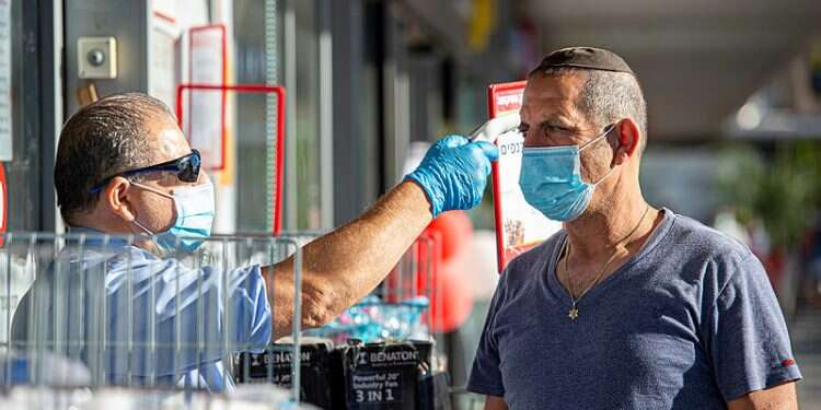 A man gets his temperature taken at the entrance to shopping center in Tiberias, Tuesday 20% of new corona cases identified in haredi sector