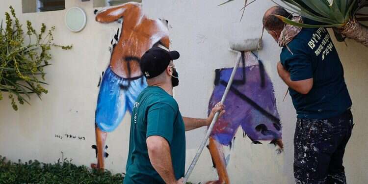Workers clean the 'Peeping Toms' mural at the beach in Tel Aviv, Aug. 23 Tel Aviv erases iconic 'Peeping Toms' beach mural after suspected gang rape