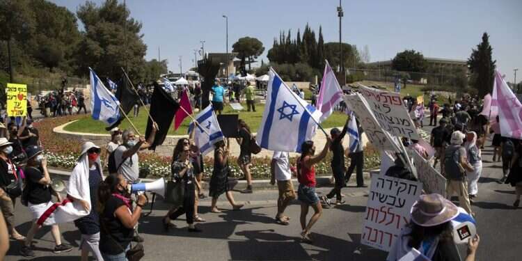 Israeli protesters wave flags and chant slogans during a demonstration against a proposed measure to curtail public demonstrations during the current nationwide lockdown due to the coronavirus pandemic, in front of the Knesset, Sept. 29, 2020 Israelis jam Jerusalem streets over bill to curb protests