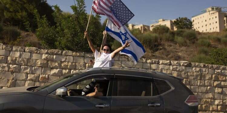 Supporters of US President Donald Trump wave an American and an Israeli flag from a car headed for a rally outside of the US Embassy in Jerusalem, Oct. 27, 2020. US allows Jerusalem-born citizens to put Israel on passports