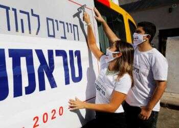 Activists from Republicans Overseas Israel, paste a pro-Trump election campaign ad on a minibus in Tel Aviv, Oct.14, 2020 White House election race reaches streets of Tel Aviv
