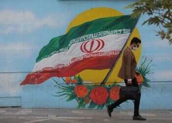 An Iranian man wearing a face mask walks on a street in Tehran Iran's coronavirus deaths exceeds 30,000