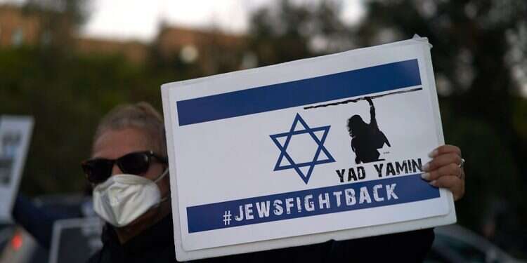 A woman holds a Jews Fight Back sign as members of the Sephardic Jewish Community in Brooklyn, New York gather to protest Mayor Bill Deblasio's closing of businesses and new lockdown in their neighborhood, Oct. 8, 2020 Poll: 69% of US Jews say Republican Party holds anti-Semitic views