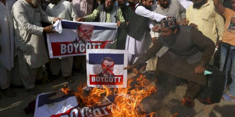 Supporters of the religious group Tahaful-e-Islam Pakistan burn representations of the French flags with defaced images of French President Emmanuel Macron in Karachi, Pakistan, Tuesday France warns citizens to be cautious as Muslim world seethes over Mohammad cartoons