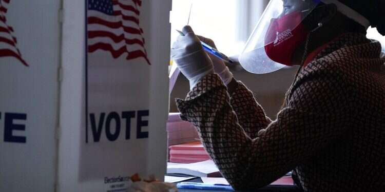A poll worker talks to a voter before they vote on a paper ballot on Election Day in Atlanta on Tuesday US Election Day unfolds smoothly, defying fears of disruption