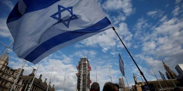 Protesters carry the Israeli flag during a demonstration against anti-Semitism in London, March 26, 2018 Finance Ministry: Israeli economy likely to grow 4.6% in 2021