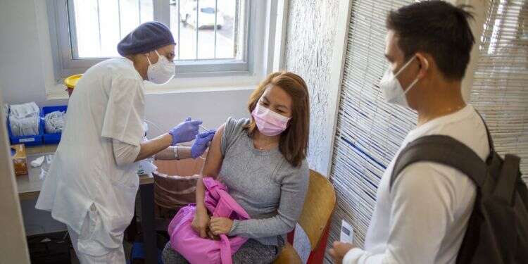 A foreign worker receives her first dose of the Pfizer-BioNTech coronavirus vaccine at a vaccination center in Tel Aviv, Feb. 9, 2021 Tel Aviv gives foreign nationals, asylum seekers COVID shots