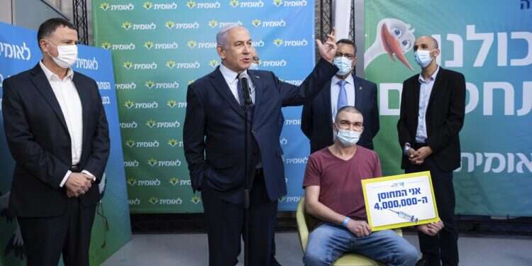 Health Minister Yuli Edelstein and PM Benjamin Netanyahu meet Theodor Salzen, the 4-millionth Israeli to be vaccinated for the coronavirus, in Jerusalem, Feb. 16, 2021 Pandemic politicking: Israel's election sprint echoes US's