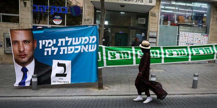 A poster of Yamina leader Naftali Bennett is seen next to signs for the left-wing Meretz party in Jerusalem, March 23, 2021 Blue and White, Labor, New Hope, Meretz consider backing Bennett