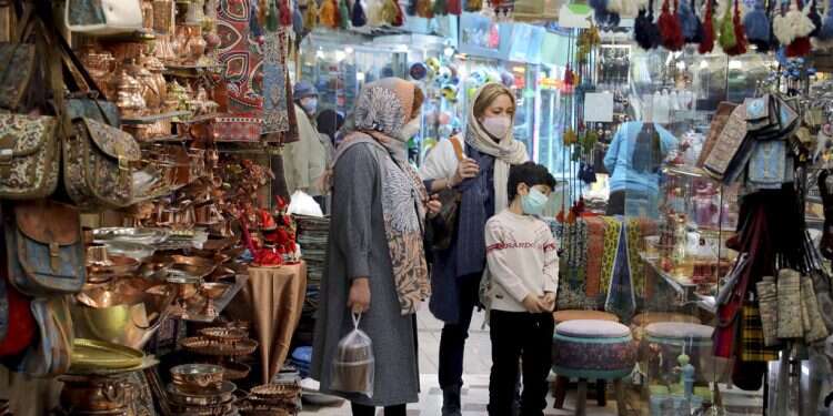 Mask-clad shoppers look at items in a shop ahead of the Persian New Year, or Nowruz, in a bazaar in Tehran, March 17, 2021 Iran braces for new COVID surge triggered by New Year celebrations