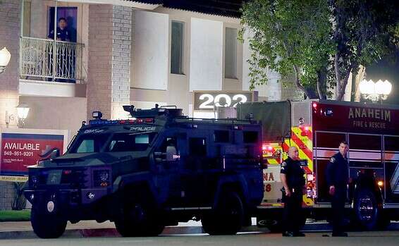 City of Orange police officers stand in front of a building after a shooting in Orange, March 31, 2021 4 dead, 2 wounded, including suspect, in shooting near Los Angeles