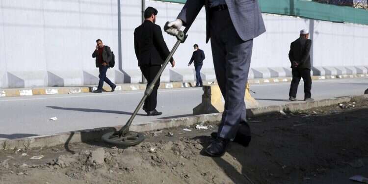 An Afghan security official looks for mines or improvised explosive device with metal detector on a roadside during a trip organized by the police for The Associated Press, in Kabul, March 17, 2021 UN chief warns that use of IEDs increasing globally