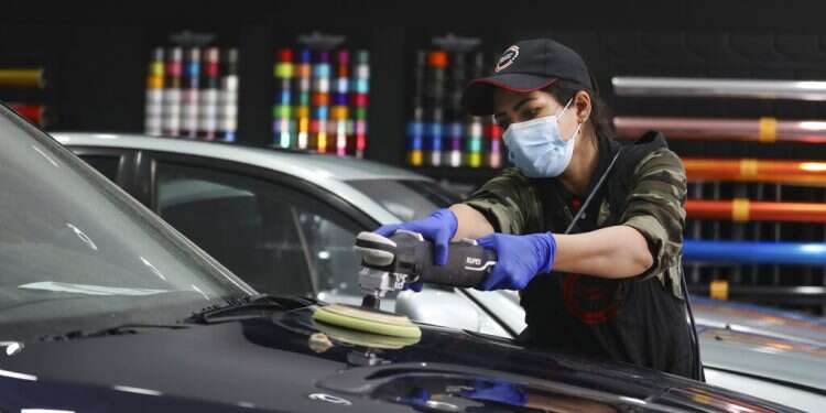 Iranian car detailer Maryam Roohani polishes a car at a detailing shop in Tehran, April 18, 2021 Iranian woman breaks taboos as she details cars at Tehran garage