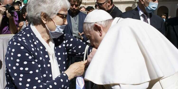 Pope Francis leans and kisses a tattoo on the arm of Holocaust survivor Lidia Maksymowicz during his weekly general audience at the Vatican, Wednesday, May 26, 2021 Pope kisses Auschwitz survivor's tattoo