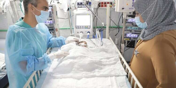 Dr. Evyatar Hubara stands by the bed of little Abdullah Al-Manar and Abdullah's mother, Lama With all their hearts