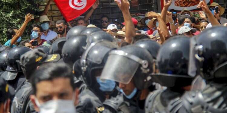 Protesters face Tunisian police officers during a demonstration in Tunis, July 25, 2021 Tensions in Tunisia after president suspends parliament, fires PM