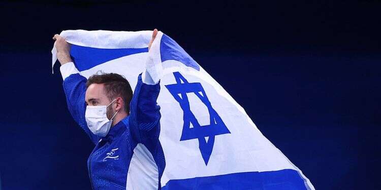 Artem Dolgopyat holds an Israel flag after winning the Olympic gold medal in the men's floor exercise, Aug. 1, 2021 Israel's Olympic gold victory raises Jewish identity debate