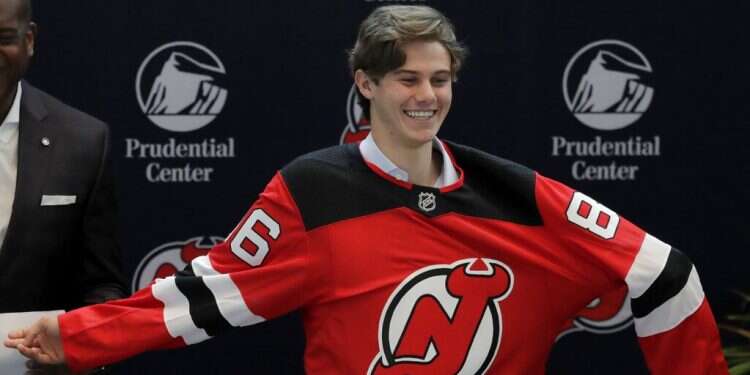 New Jersey Devils forward Jack Hughes, the No. 1 overall pick in the NHL draft, puts on a jersey during a news conference introducing the prospect to local media in Newark, NJ on June 25, 2019 Trio of Jewish brothers make NHL draft history