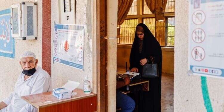Iraqi woman scans her finger to verify her identity before voting at a polling station during the parliamentary election, in Kerbala, Iraq, Oct. 10, 2021 Slow turnout at Iraqi election reflects apathy among voters