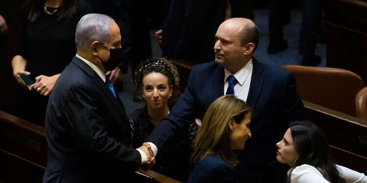 Prime Minister Naftali Bennettut shakes hands with Opposition Leader Benjamin Netanyahu after parliament voted to approve the new government on June 13, 2021 Any term limit legislation must be part of larger reform