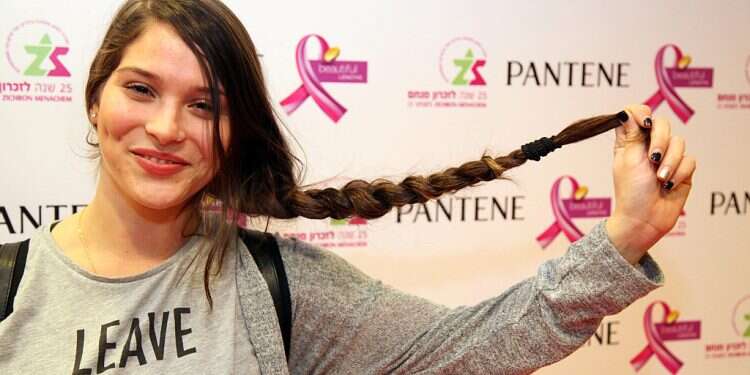 Rotem Shvili holds up her long braid before donating her hair to Zichron Menachem in 2015 to be used for wigs for cancer patients Hair donations for cancer patients down 40% due to COVID