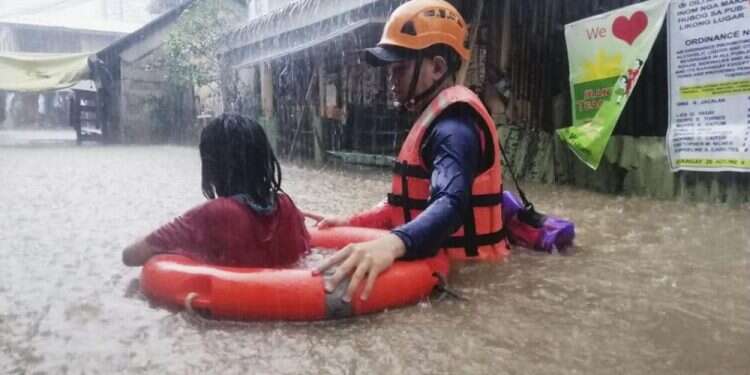 A rescuer assists a girl as they wade through flooding caused by Typhoon Rai in Cagayan de Oro City, southern Philippines, Dec. 16, 2021 Powerful typhoon hits Philippines, nearly 100,000 evacuated