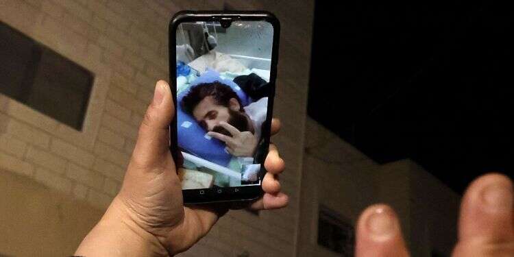 Palestinians speak in a video call with hunger-striking Islamic Jihad prisoner Hisham Abu Hawash, lying in an Israeli hospital, Jan. 4, 2022 Report: Israel agrees to release hunger-striking PIJ security prisoner