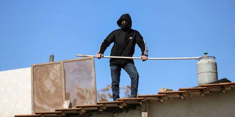 A Palestinians takes to the roof of a home, threatening to blow up the dwelling with a gas balloon after police arrive to carry out an eviction order, in the flashpoint Sheikh Jarrah neighborhood of east Jerusalem, Jan. 17, 2022 Palestinian threatens to burn Sheikh Jarrah home rather than be evicted