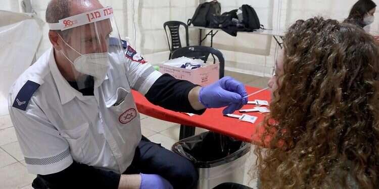 A Magen David Adom paramedic tests a woman for COVID at a new site in Habima Square in Tel Aviv on Jan. 4 2022 All COVID numbers rising, 247 patients in serious condition