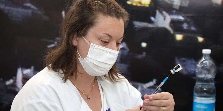 A medical worker prepares to administer a dose of Pfizer's coronavirus vaccine at a Tel Aviv Clalit vaccination site, March 2, 2021 Israeli study: Women twice as likely to report side effects from COVID vaccine
